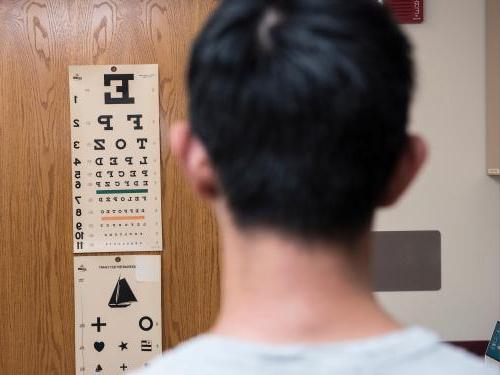 A patient stands in front of the eye exam chart at the clinic.